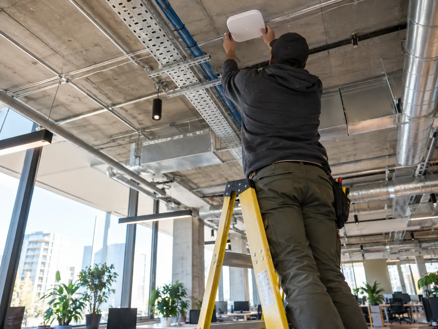 Technician installing a ceiling-mounted wireless access point